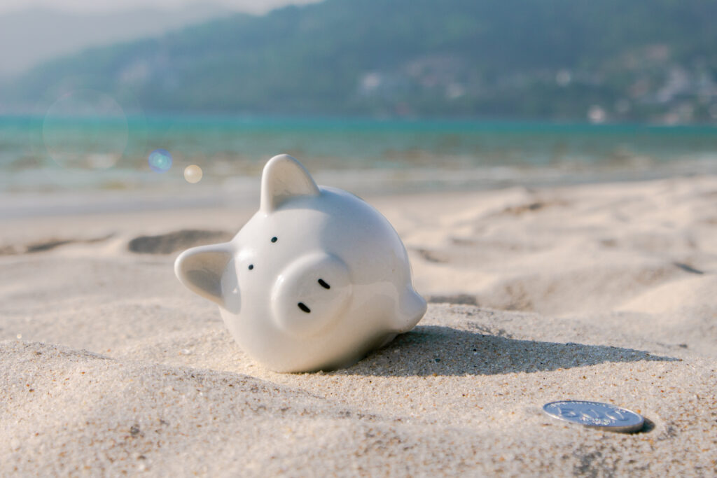 piggy bank sinking in sand on a beach